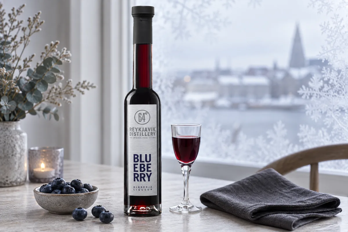 A recognizable Reykjavik Distillery Blueberry liqueur bottle beside a small ruby cordial and fresh blueberries at a frosted Nordic window.