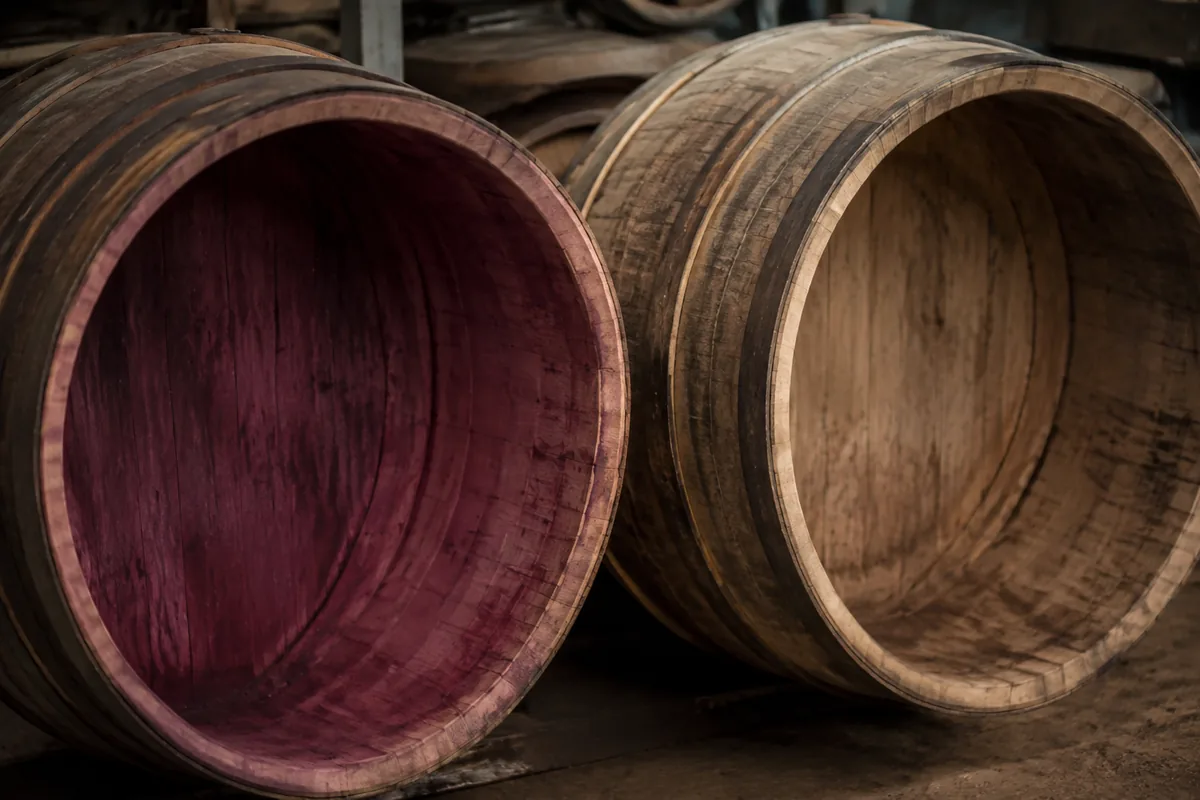 Two open oak casks side by side, one deeply wine-stained inside and one paler after repeated use.